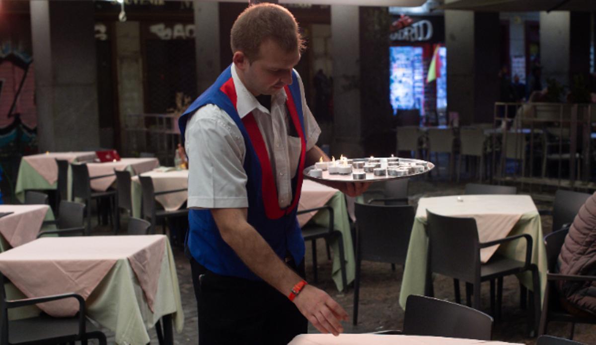 Un camarero prepara las mesas antes de la apertura del local.