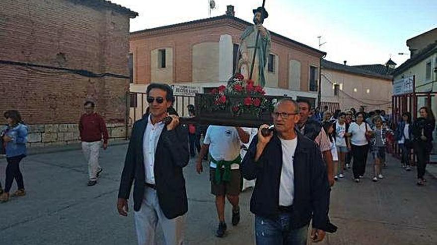 A la izquierda, vecinos portan la imagen de San Roque en la procesión del año pasado. A la derecha, desfile de peñas por las calles del municipio.