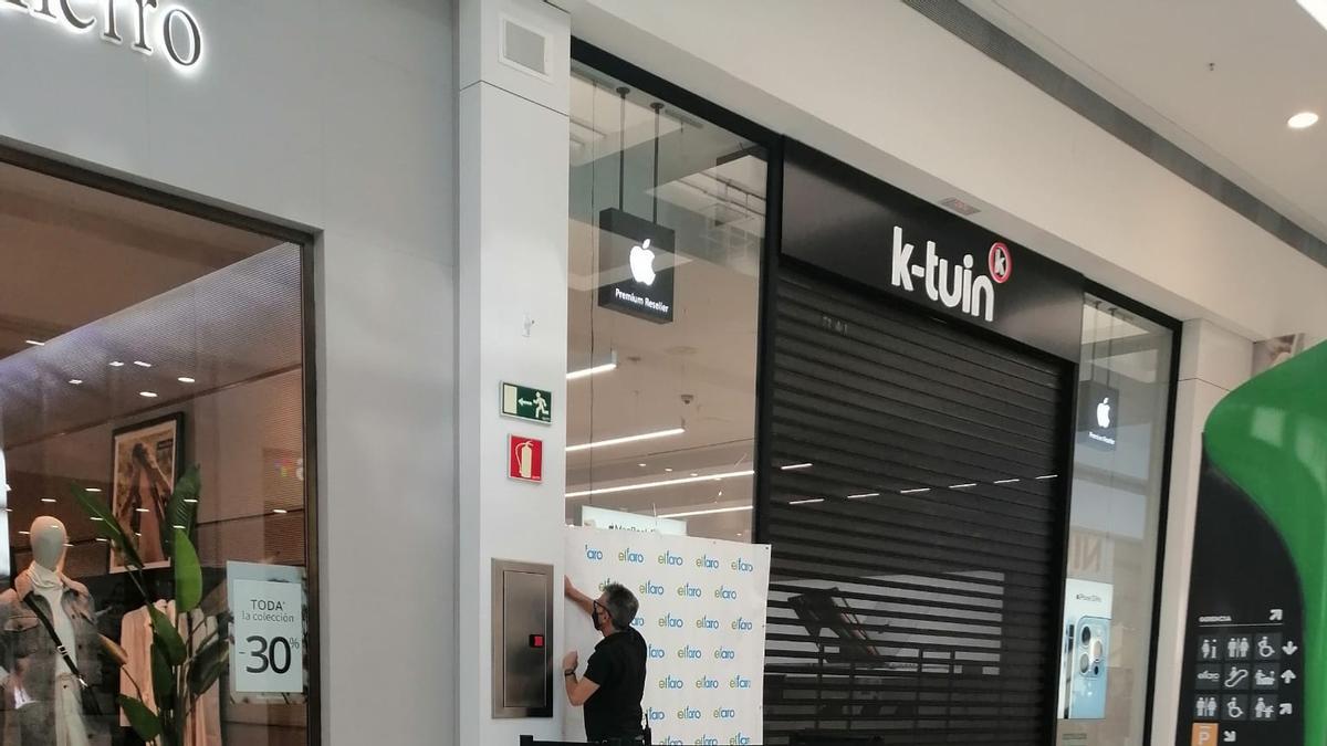 Un operario revisa la luna de la tienda de telefonía que ha sufrido el robo esta madrugada.