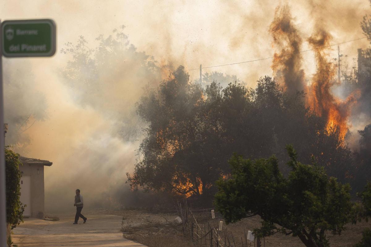 Un hombre escapa ante la proximidad del fuego, en el incendio de Montitxelvo de 2023.