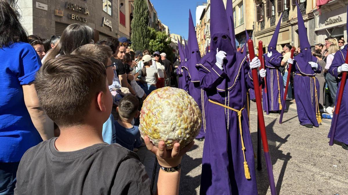Un niño con una bola de cera gigante en la Tribuna de los Pobres, al paso de la cofradía del Rocío.