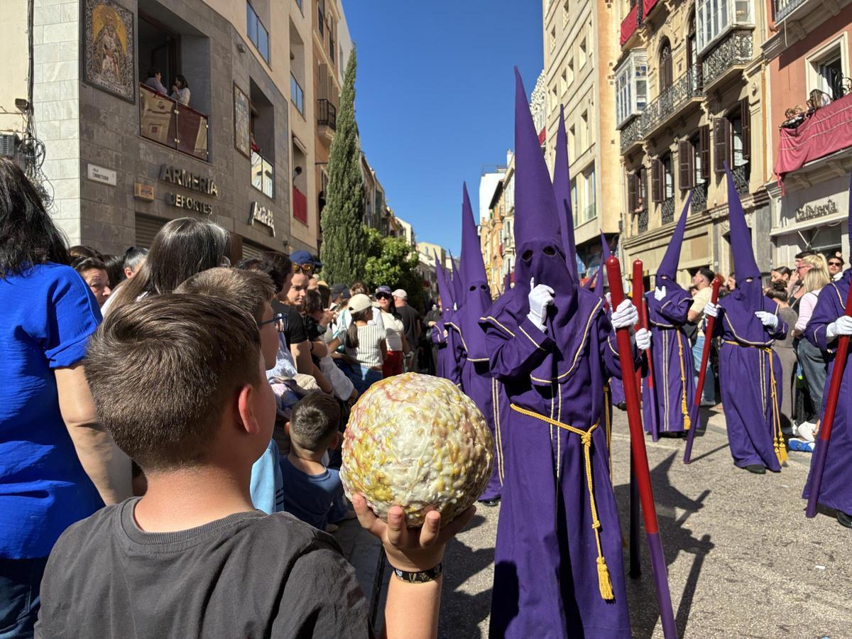 Un niño con una bola de cera gigante en la Tribuna de los Pobres, al paso de la cofradía del Rocío.