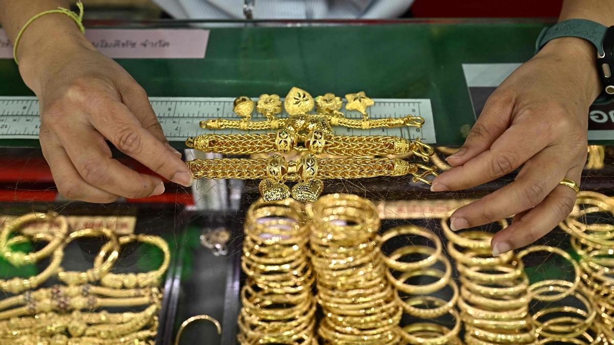 Una persona coloca joyas de oro en el mostrador