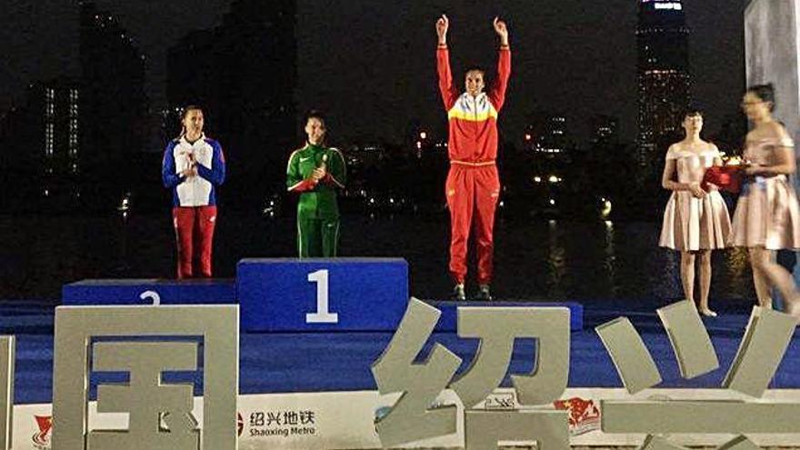 Eva Barrios eleva los brazos al cielo chino para celebrar en el podio su medalla de bronce.