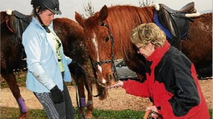 Victorina Posa donant un tros de pastanaga a l&#039;Estel, el cavall de Paquita Abarca, que s&#039;ho mira al costat