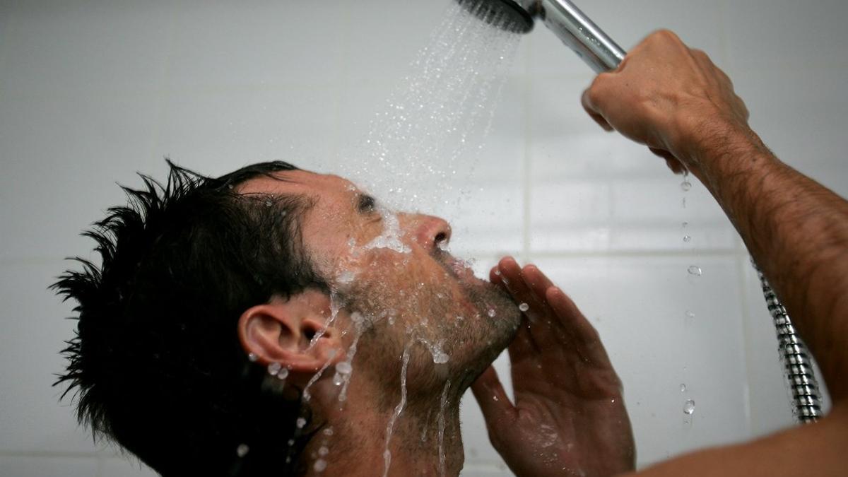 Un hombre se lava la cara en la ducha.