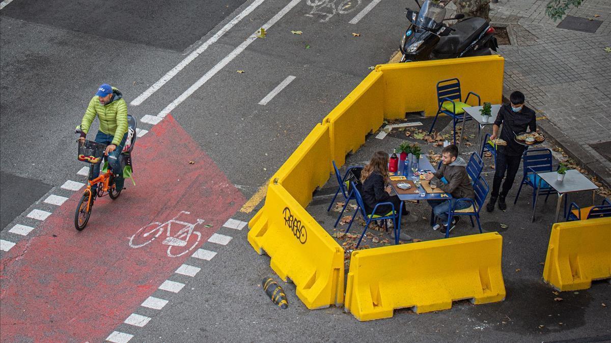 Una terraza de restaurante ampliada en la calzada a partir de barreras New Jersey pintadas de amarillo. 