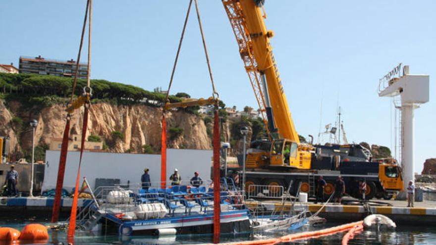 Una gran grua reflota el vaixell enfonsat, ahir al port de Sant Feliu de Guíxols.