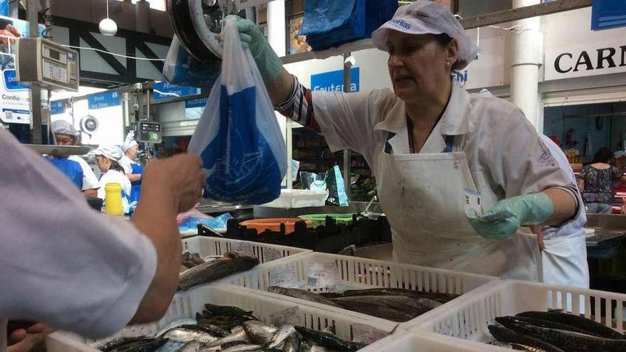Una pescantina de la plaza de abastos de Bueu atiende a un cliente que acude a comprar pescado. // G.N.