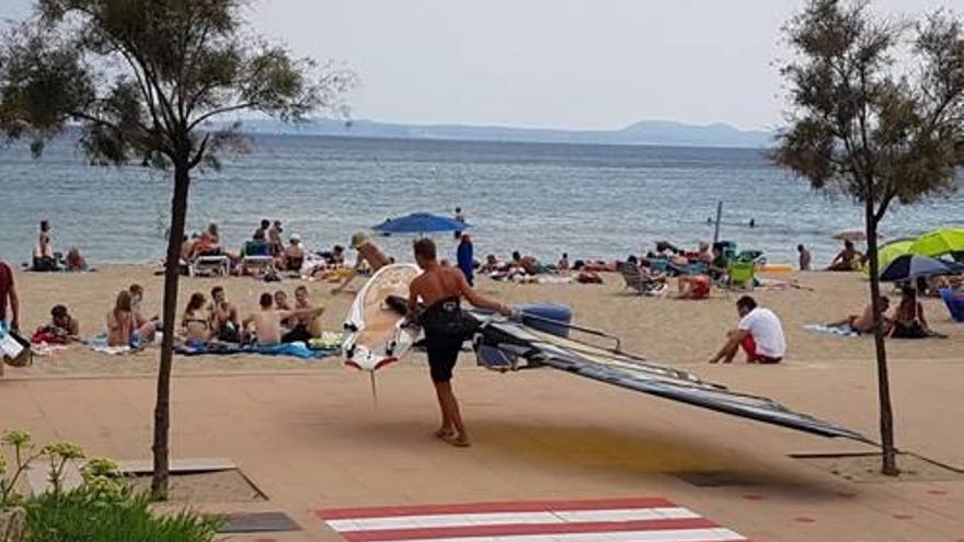 Un esportista, passant per la platja amb la vela.