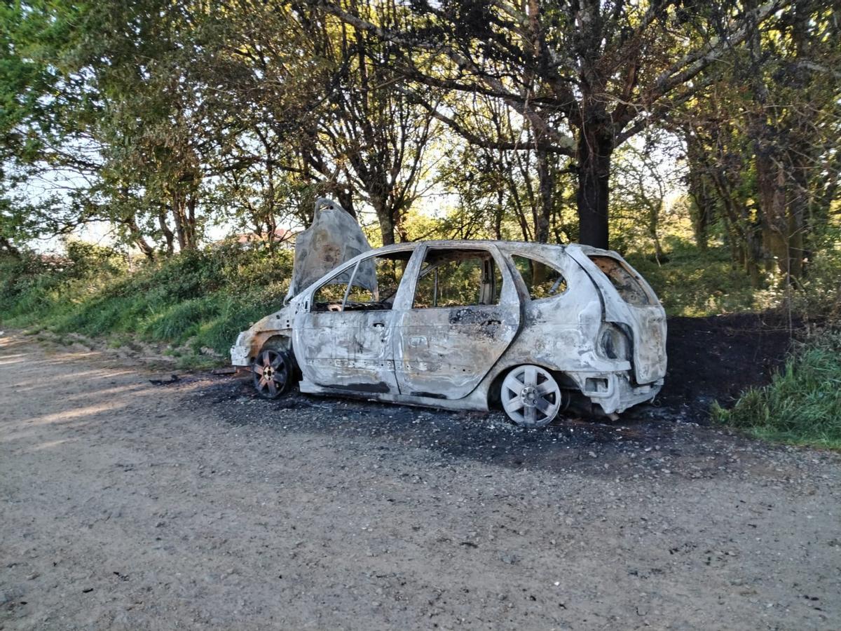 Coche calcinado después del fuego presuntamente intencionado desencadenado en la madrugada de hoy en Sigüeiro (Oroso)
