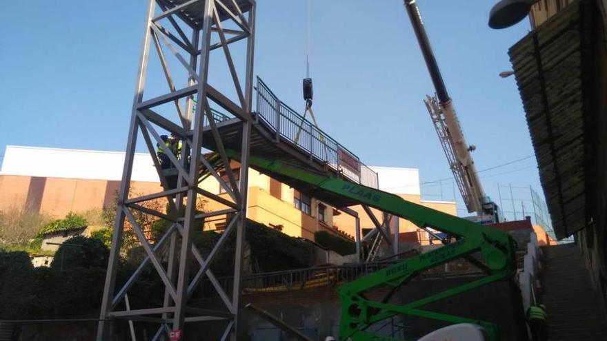 La grúa coloca la pasarela que permitirá el acceso a la parte superior de la calle desde el ascensor.