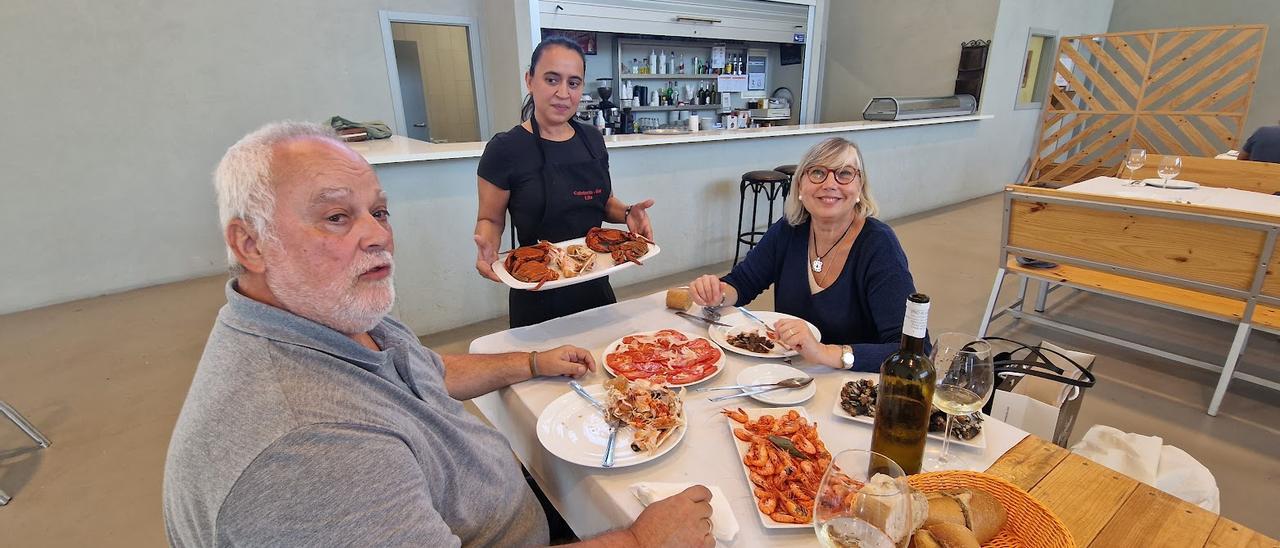 Rita Cal sirviendo nécoras a Teresa y Ramón, dos turistas vascos que se confiesan “encantados” con la experiencia.   | //  M. MÉNDEZ