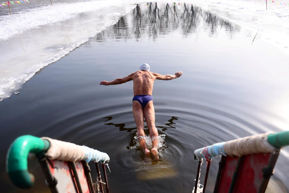 Winter swimmer dives into icy waters at a park ...