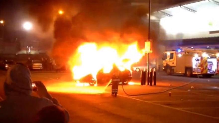 Los bomberos intentan apagar el fuego del coche.