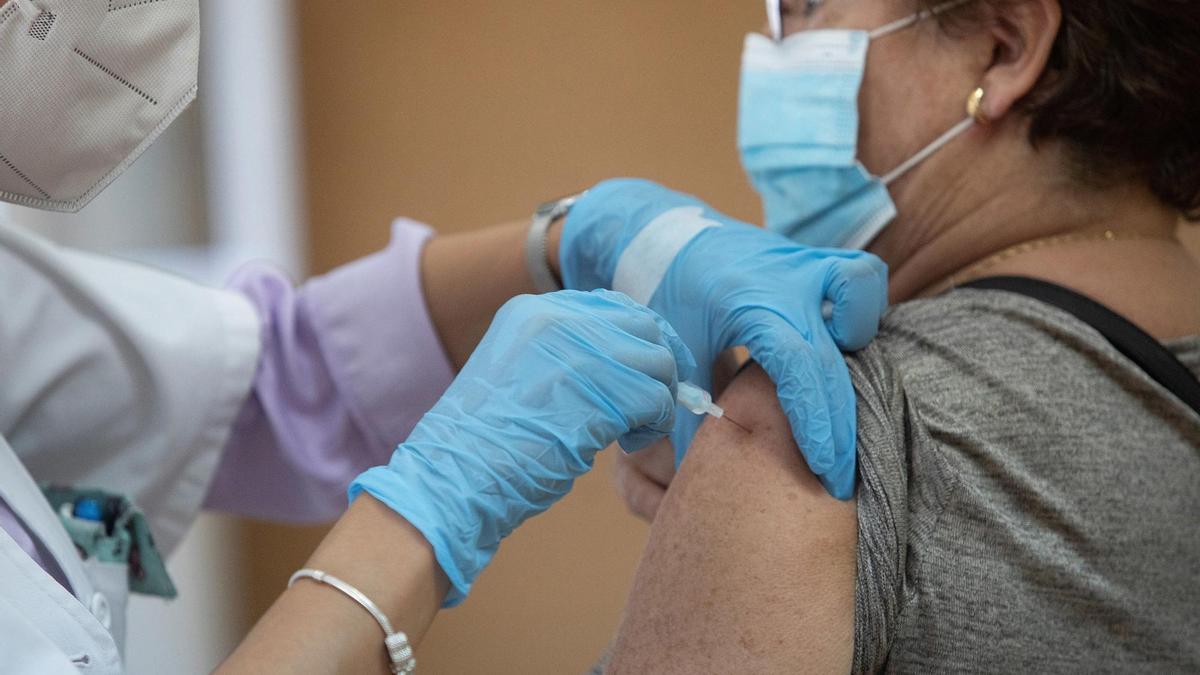 Una enfermera vacuna a una mujer contra la gripe y el covid.