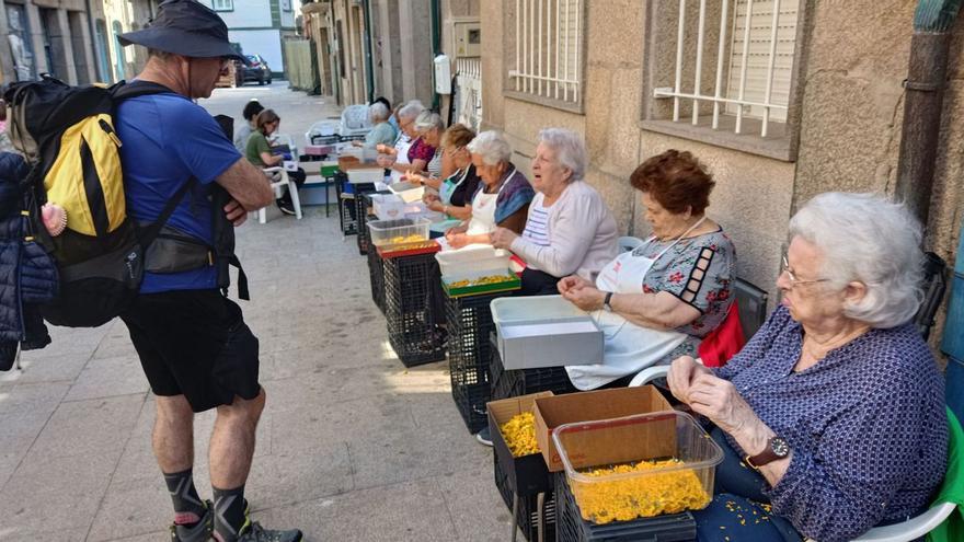 Un peregrino se interesa por la labor de las alfombristas, ayer, en la calle Isidoro Queimaliños.   // ANTONIO PINACHO