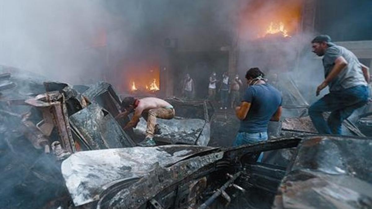 Civiles libaneses y equipos de emergencia, en el lugar de la explosión, ayer, en Beirut.