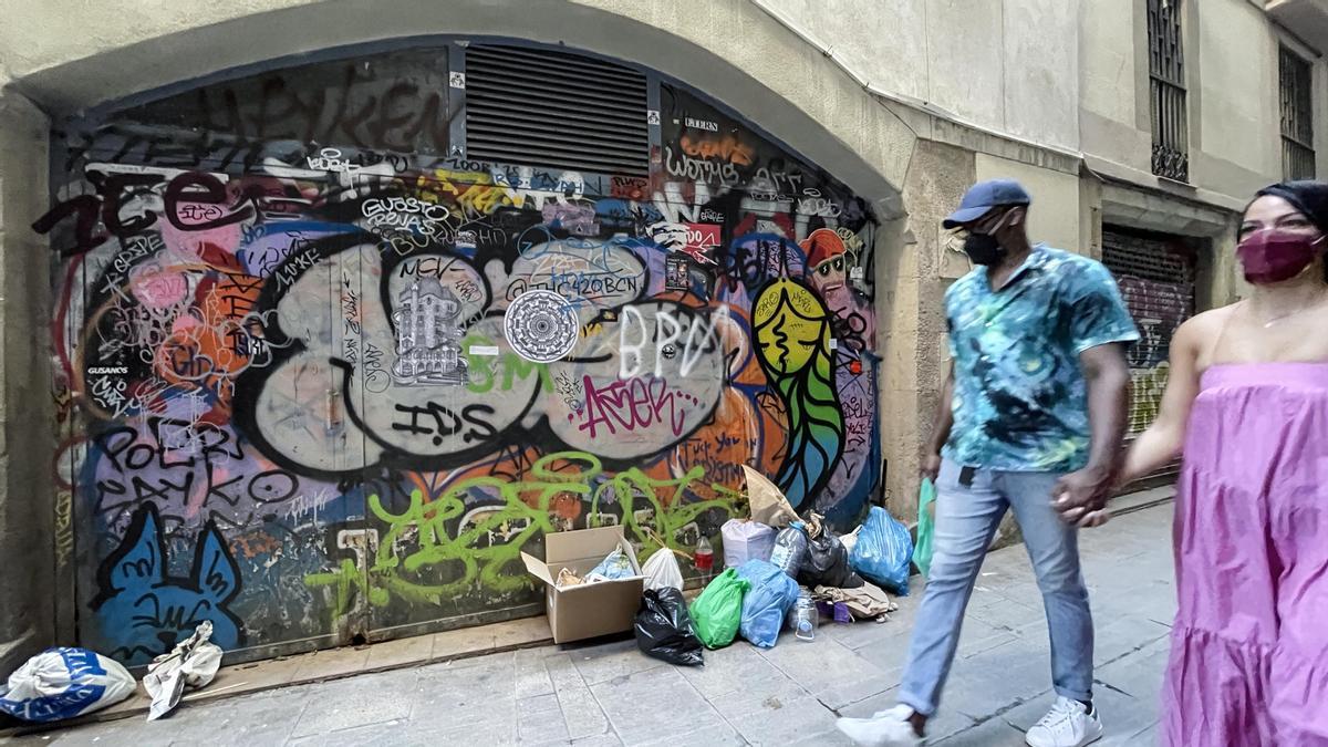 Bolsas de basura y pintadas en el carrer dels Escudellers Blancs, en Ciutat Vella