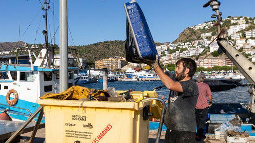 Un pescador buidant alguns dels residus que s&#039;han trobat a alta mar en el Port de Roses