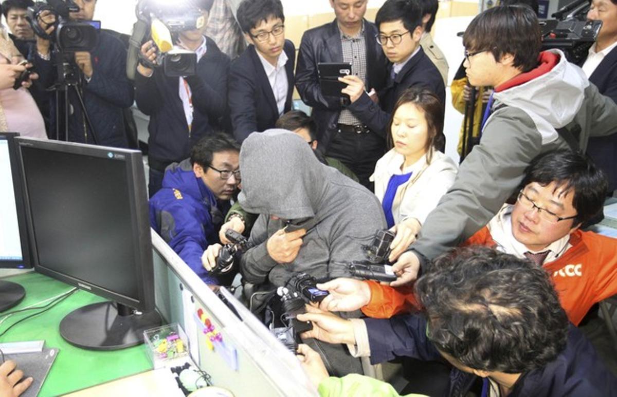 El capità del ’Sewol’, Lee Joon-Seok, amb caputxa i envoltat de periodistes, a la comissaria de Mokpo, aquest dijous.