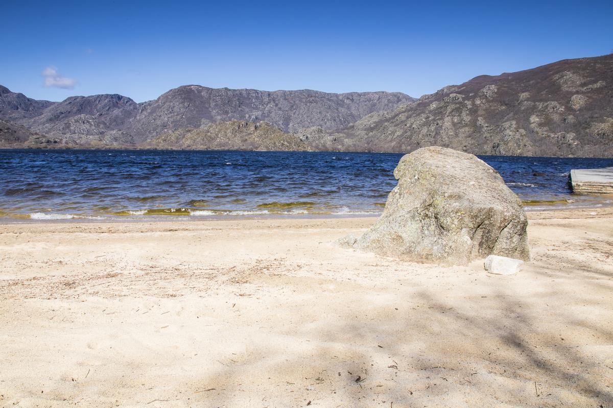 Playa de arena blanca del lago de Sanabria con una gran roca