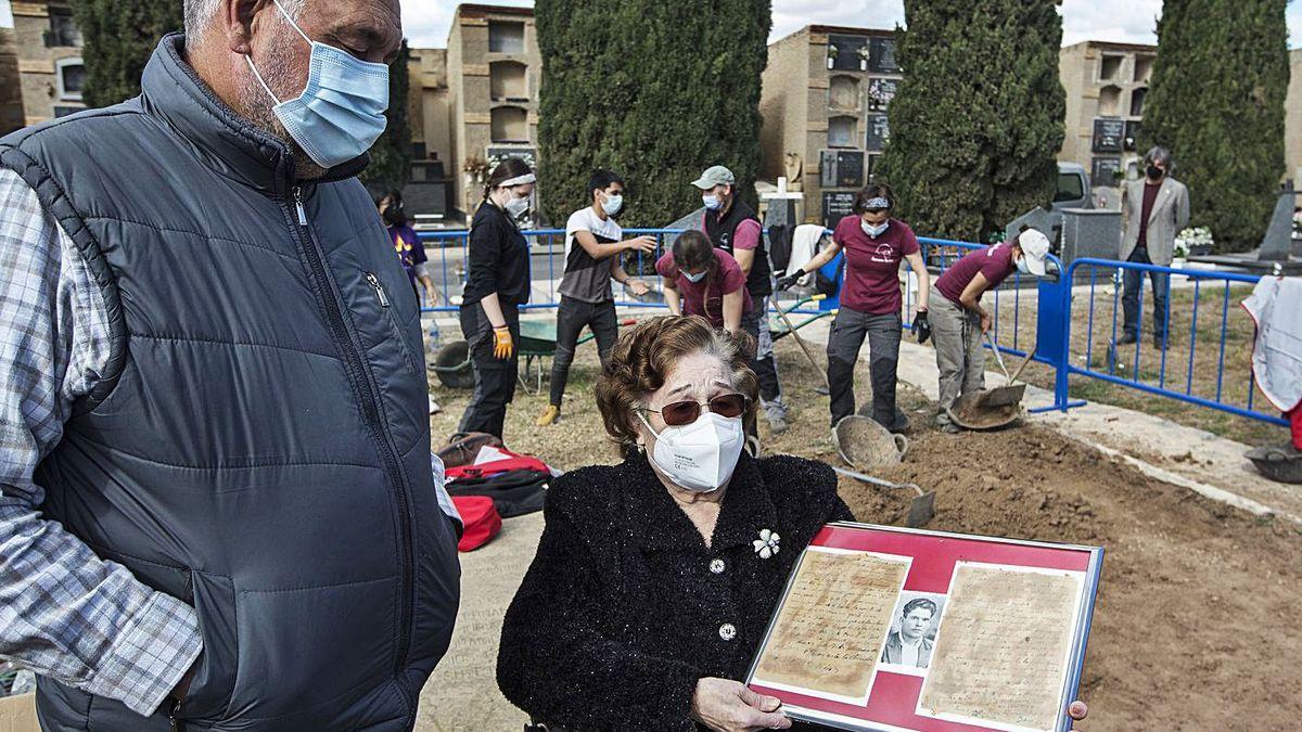 María Ros, junto a las excavaciones en el cementerio, con una foto de su padre y las dos últimas cartas que escribió antes de ser fusilado.