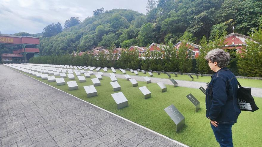 Una visitante observa las placas del Memorial Minero del pozo Sotón, con el castillete al fondo. | A. Velasco
