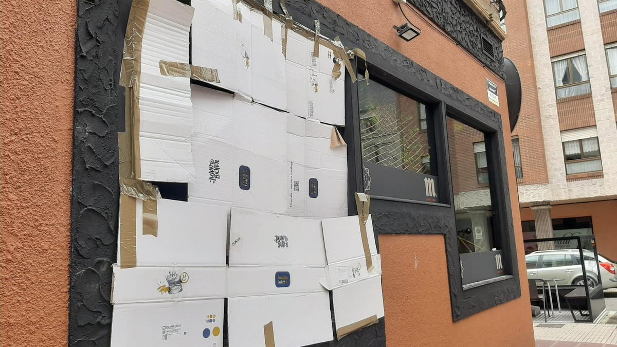 La cristalera del bar asaltado esta mañana tapada con cartones