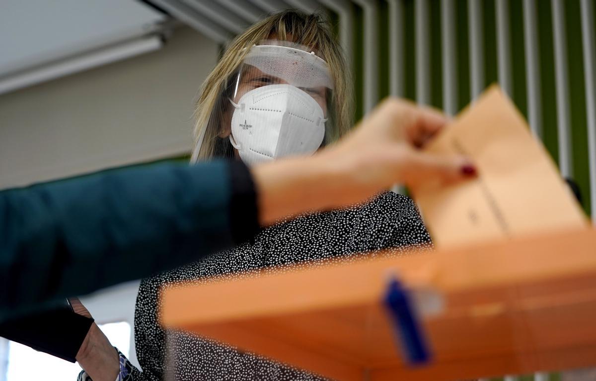 La presidenta de una mesa electoral en el colegio de La Inmaculada de Madrid, con máscara facial contra el coronavirus.