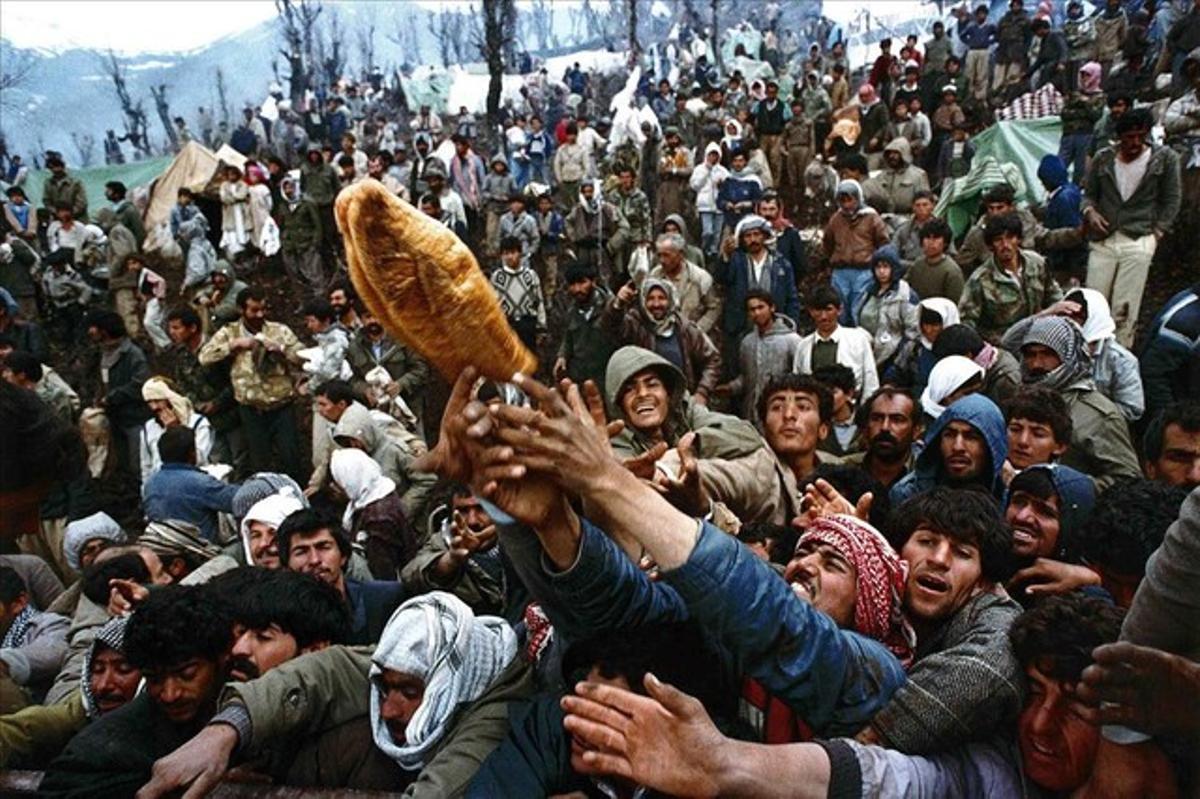 Frantic Kurdish refugees struggle for a loaf of bread during a humanitarian aid distribution at the Iraqi-Turkish border in this April 5, 1992 file photo.