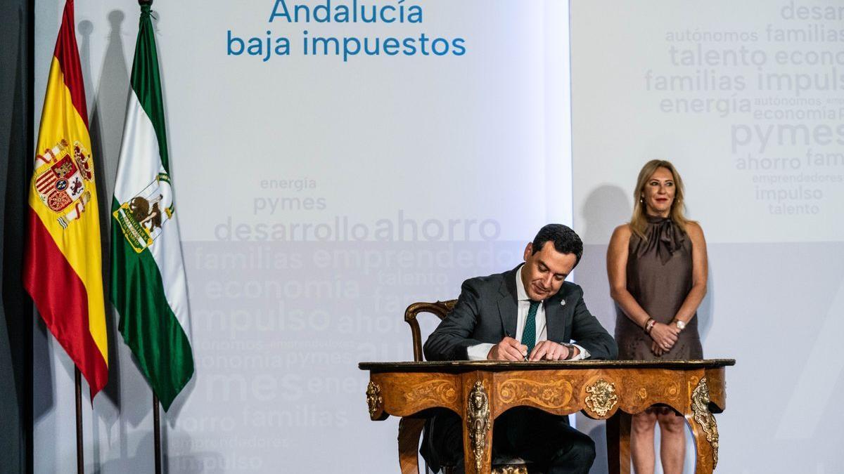 Moreno firma el decreto ley de bajada de impuestos junto a la consejera de Economía y Hacienda, Carolina España.