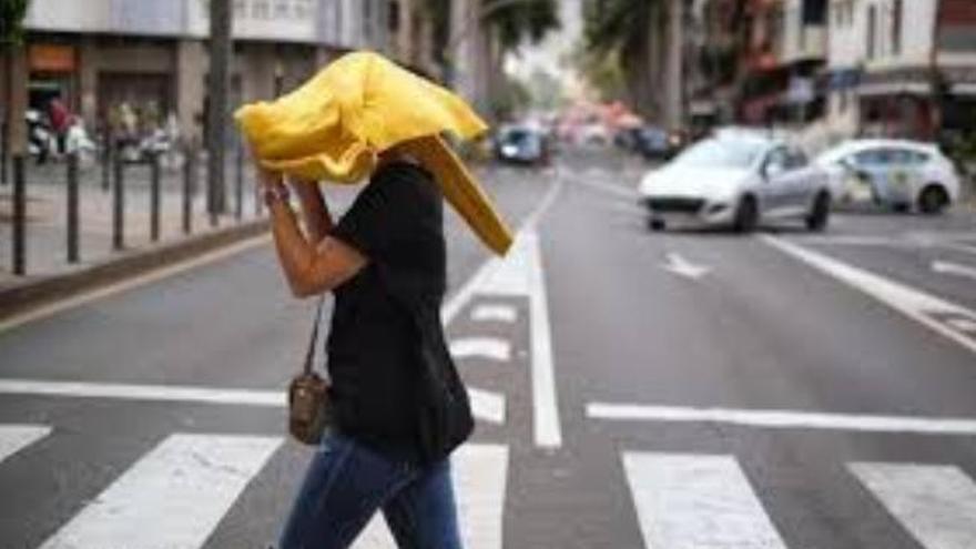 Una mujer se proteje de la lluvia con un improvisado paraguas.