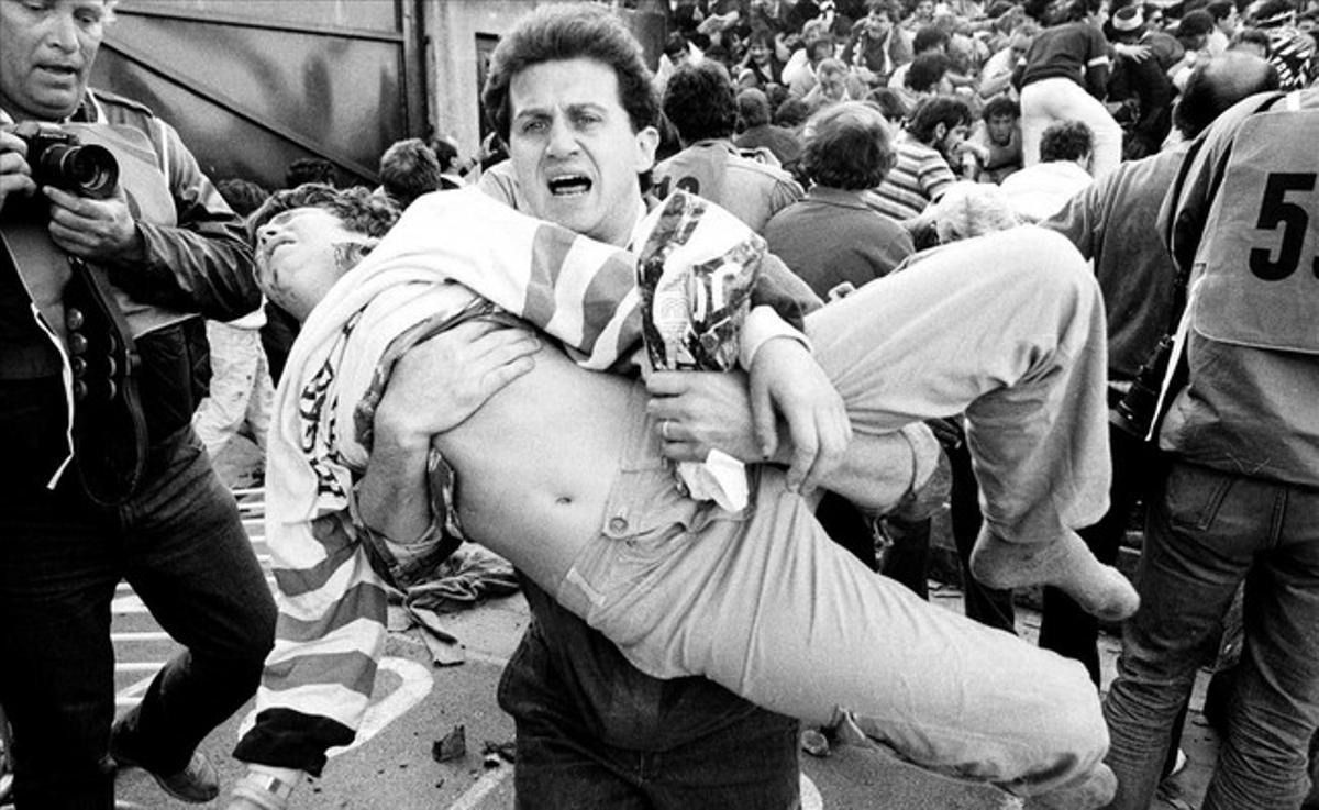 An injured soccer fan is carried to safety by a friend after a wall collapsed during violence between fans before the European Cup final between Juventus and Liverpool in this May 29, 1985 file photo at the Heysel stadium in Brussels. 39 people died, and a further 600 were injured.