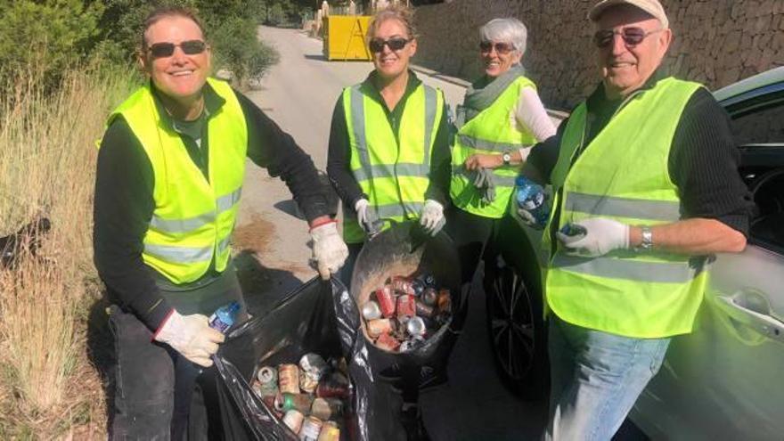 Un grupo de voluntarios muestra las latas recogidas.