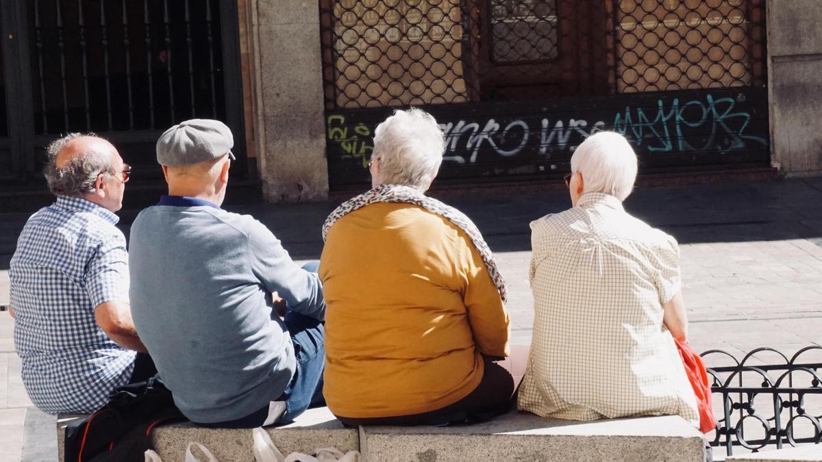 Cuatro vecinos de Salamanca conversan en un banco.