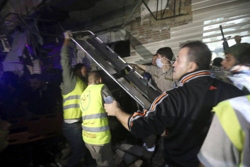 Civil Defense members carry a stretcher through a damaged area caused by two explosions in Beirut's southern suburbs, Lebanon