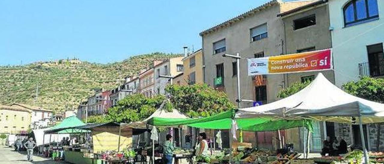 Puestos del mercado semanal en la localidad leridana de Torà este viernes, entre carteles independentistas; a la derecha, el alcalde del municipio, Magí Coscollola.