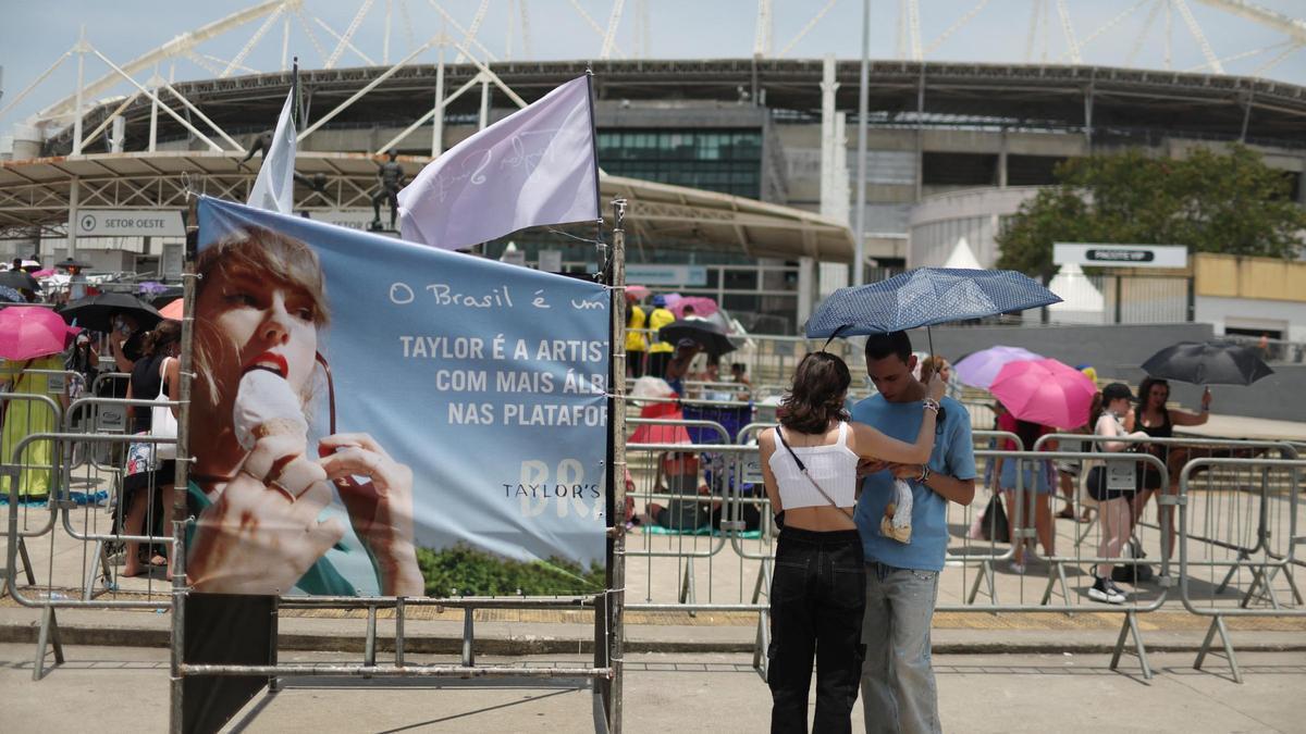 PUna pareja se resguarda con un paraguas por las altas temperaturas de Rio de Janeiro antes del show de Taylor Swiift