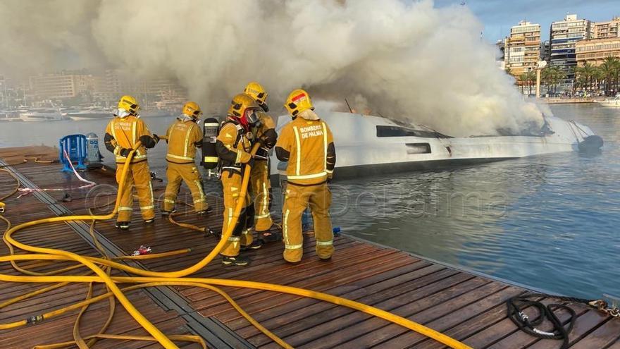 Feuerwehrleute löschen den Brand auf einem Katamaran im Hafen von Palma de Mallorca.