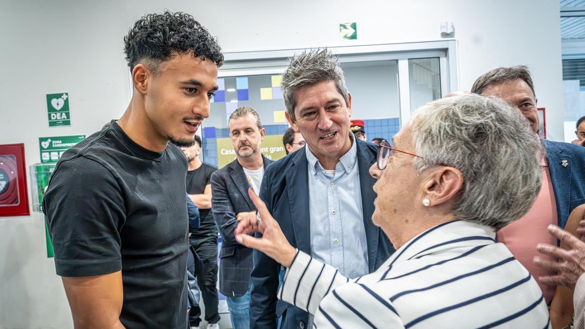 Omar El Hilali, jugador del RCD Esapnyol, y David Quierós, alcalde de L'Hospitalet, conversan con una vecina durante la presentación de la Red Antirumores de L'Hospitalet.