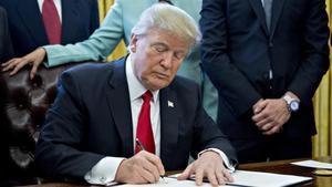 El presidente de Estados Unidos, Donald Trump, firma una orden ejecutiva en el despacho oval. 