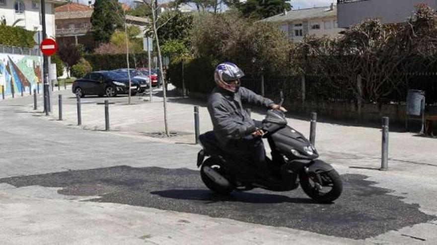 Un ciclomotor y su piloto, sobre uno de los parches de asfalto entre las losetas de la calzada.  // José Lores