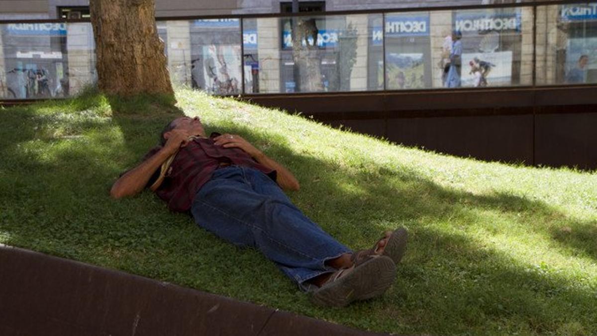 Un joven hace la siesta en una plaza de Barcelona, en una imagen de archivo.
