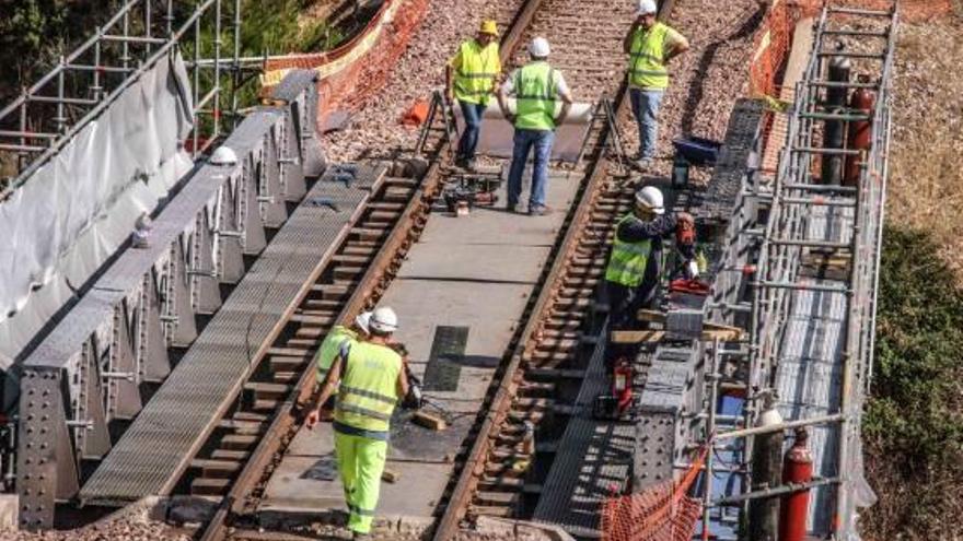 Operarios trabajando en el refuerzo de un puente metálico de la línea ferroviaria.