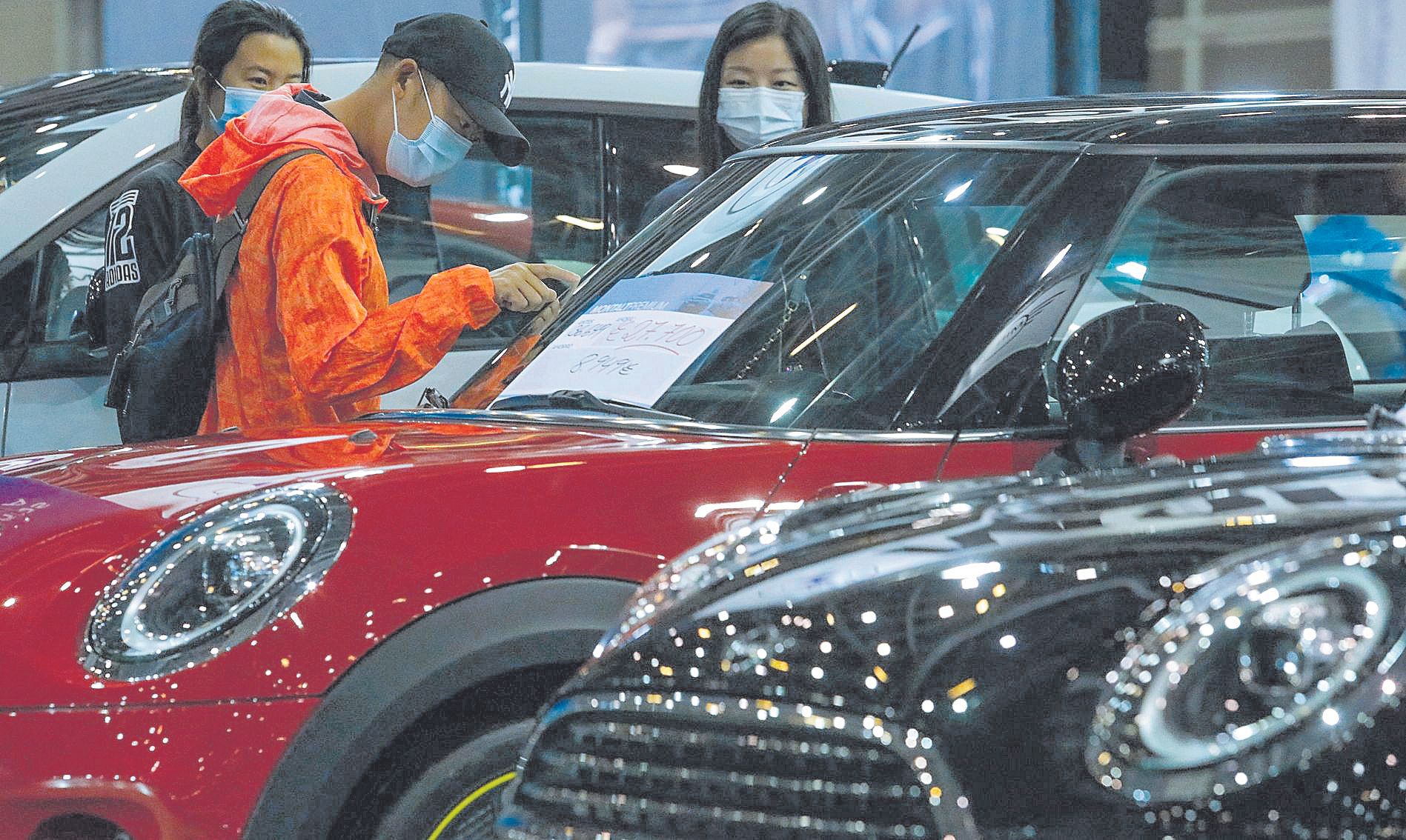 Visitantes en la Feria del Automóvil de València de 2021, una edición que fue todo un éxito de ventas y afluencia por la escasez de coches nuevos. En el centro, dos clientes con muebles de segunda mano. Y una tienda de ropa en València