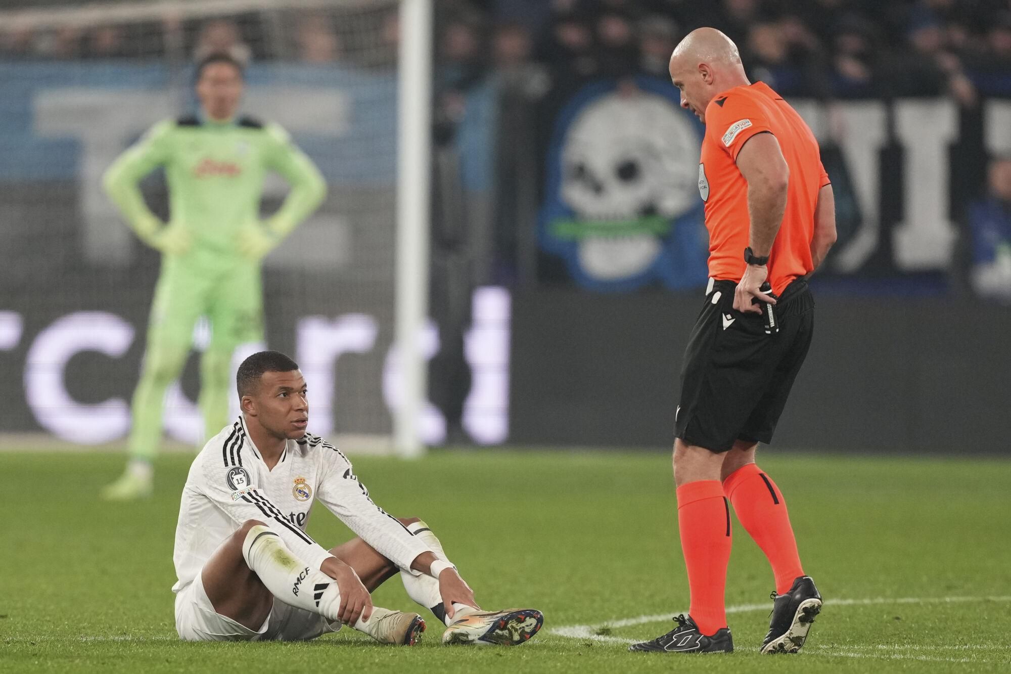 Real Madrid's Kylian Mbappe, left, talks with referee Szymon Marciniak during the Champions League opening phase soccer match between Atalanta and Real Madrid at the Bergamo's stadium, in Bergamo, Italy, Tuesday, Dec. 10, 2024. (AP Photo/Antonio Calanni). EDITORIAL USE ONLY/ONLY ITALY AND SPAIN