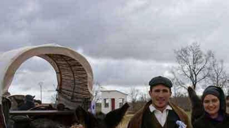 Una pareja junto a un carro con el burro.