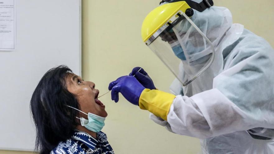 Un trabajador sanitario realiza una prueba de coronavirus a una mujer en Indonesia.