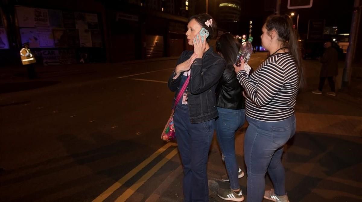 Asistentes del concierto llaman por teléfono tras salir del recinto del Manchester Arena.